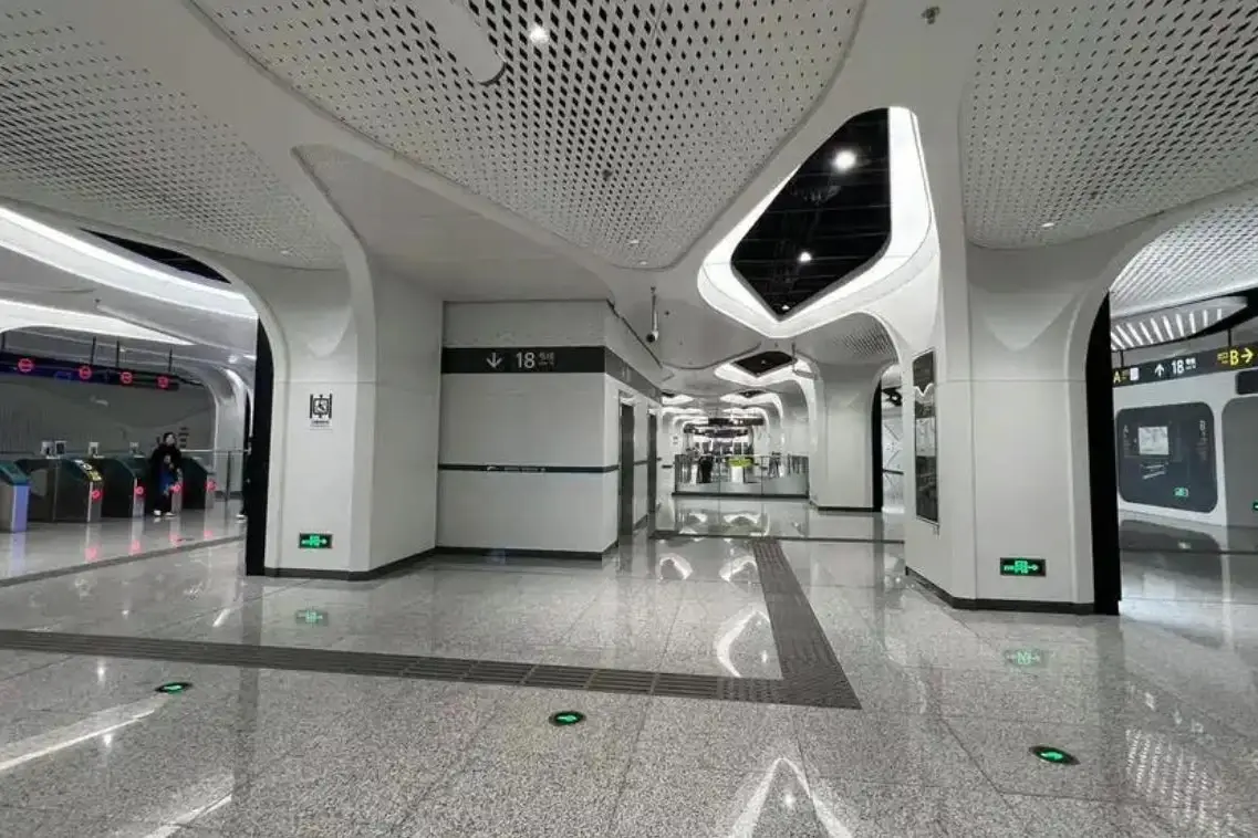 Metro station concourse with white crystallized glass walls and sculpted column cladding