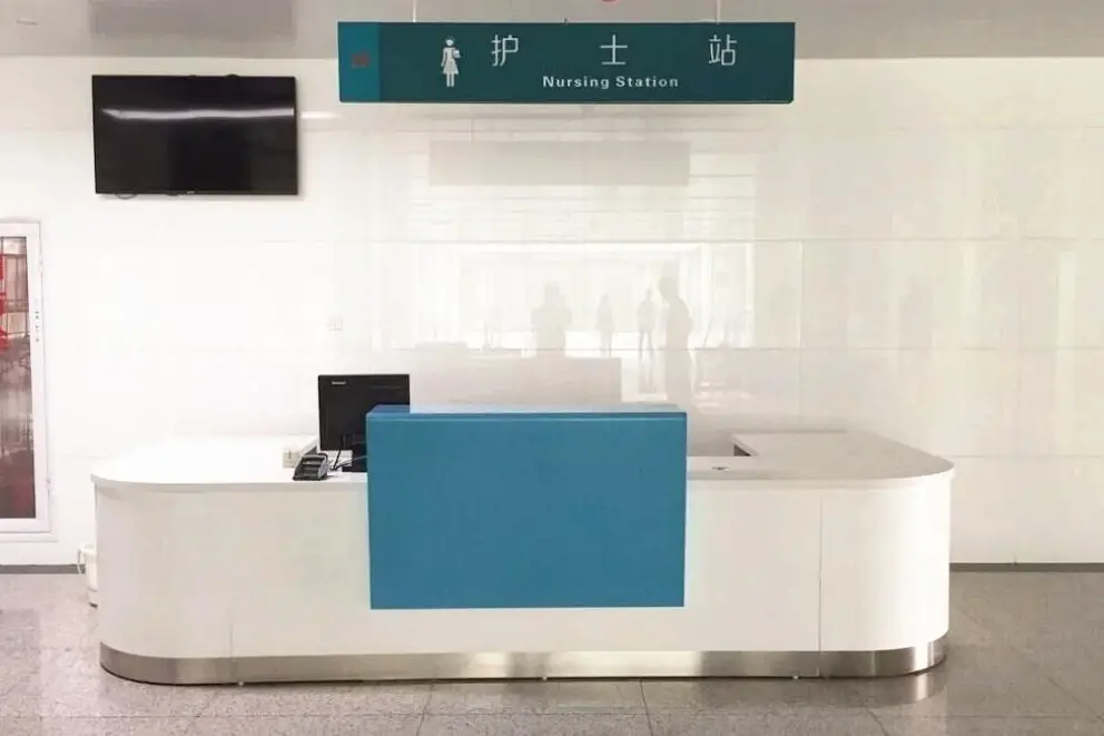 Hospital nursing station with a white curved counter and white wall panels