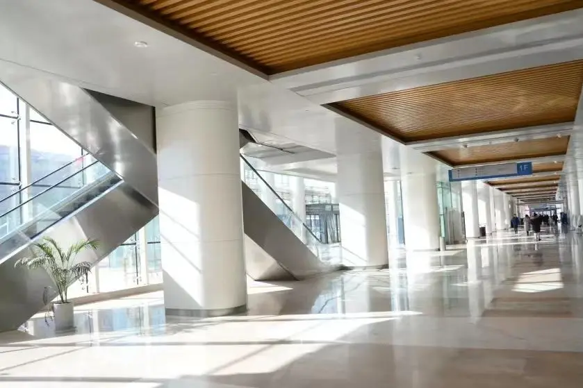 Bright hospital hall with white wall surfaces and clad columns beside escalators