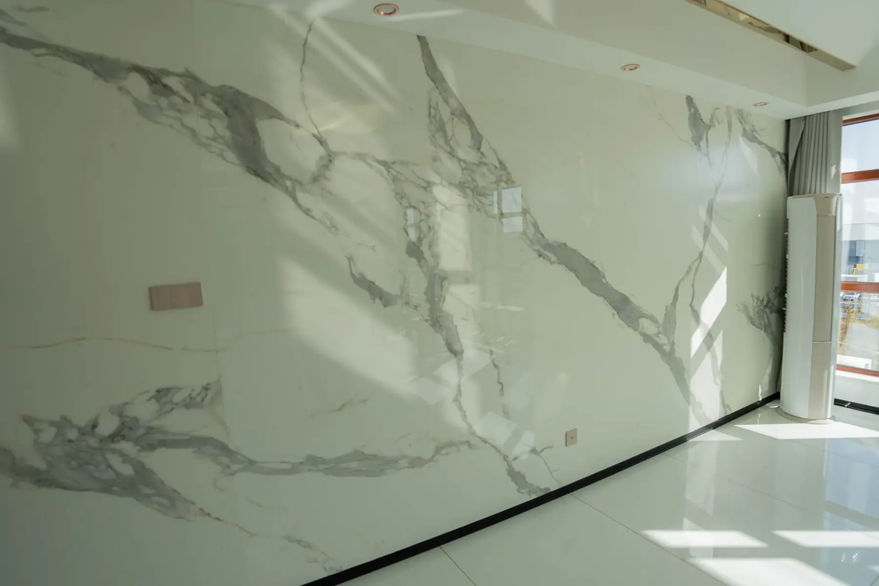 Floor-to-ceiling crystallized glass wall with grey and white marble-look veining in a sunlit room
