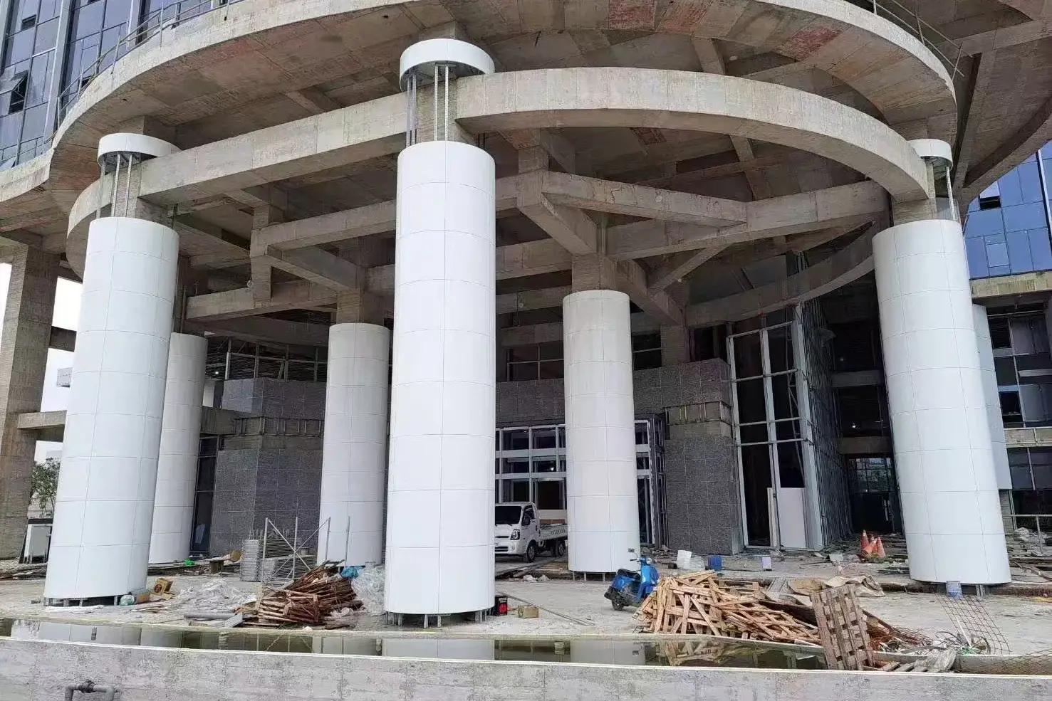 Tall round columns clad in white crystallized glass segments on a building site