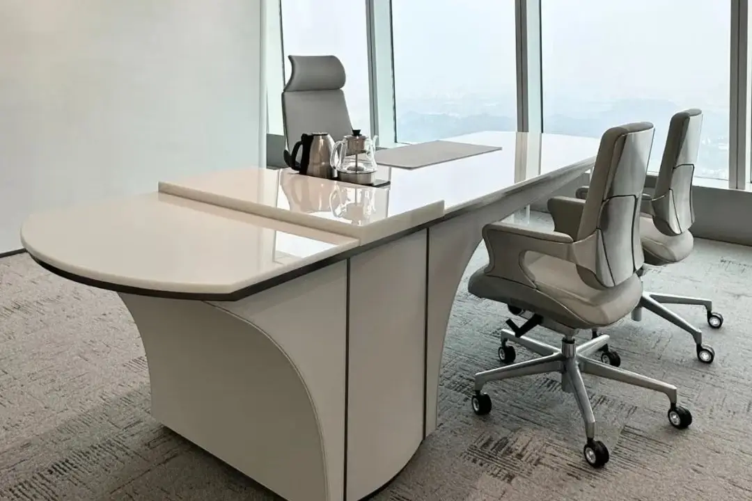 White crystallized glass office desk with a curved end beside a window
