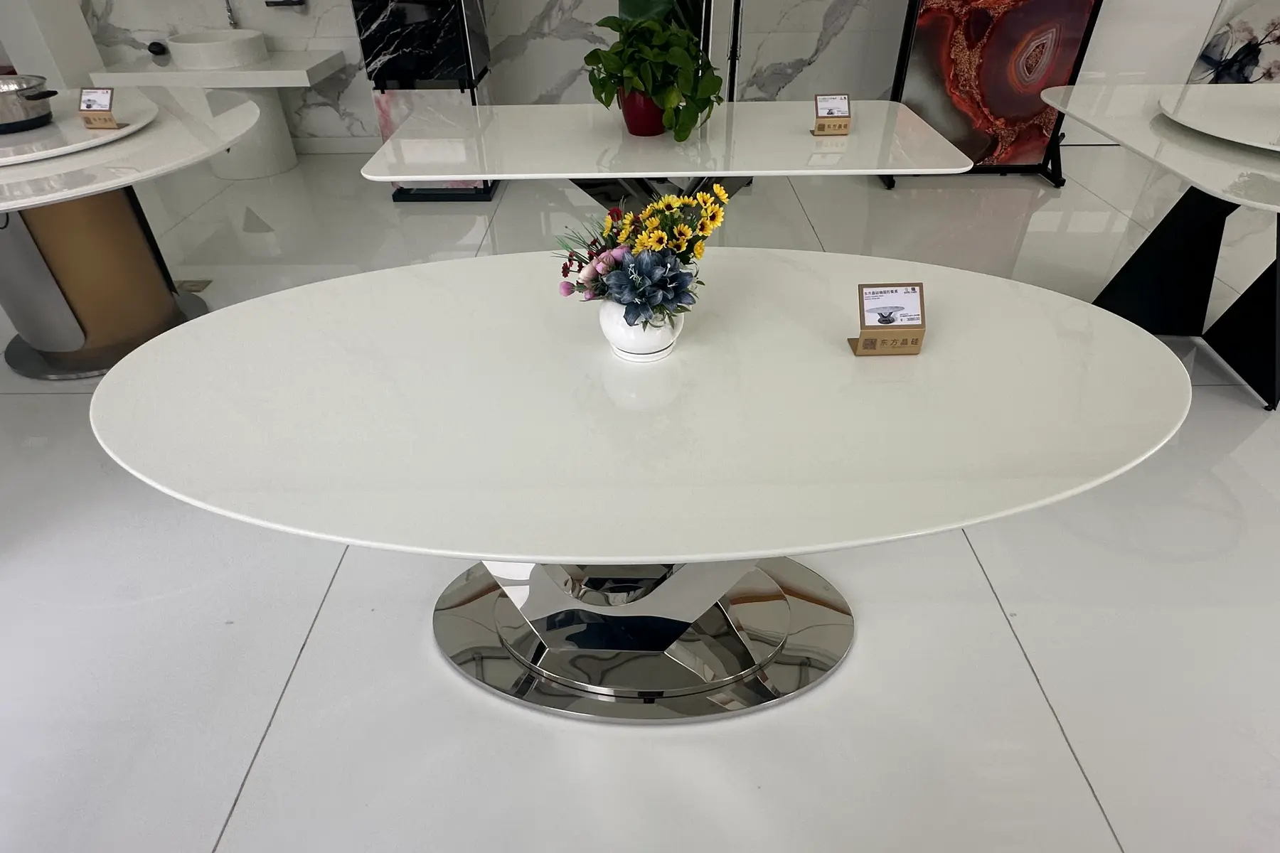 Large oval white table top on a polished steel base in a showroom