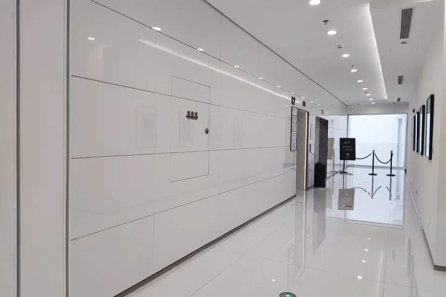Bright corridor lined with large white crystallized glass wall panels and a polished white floor