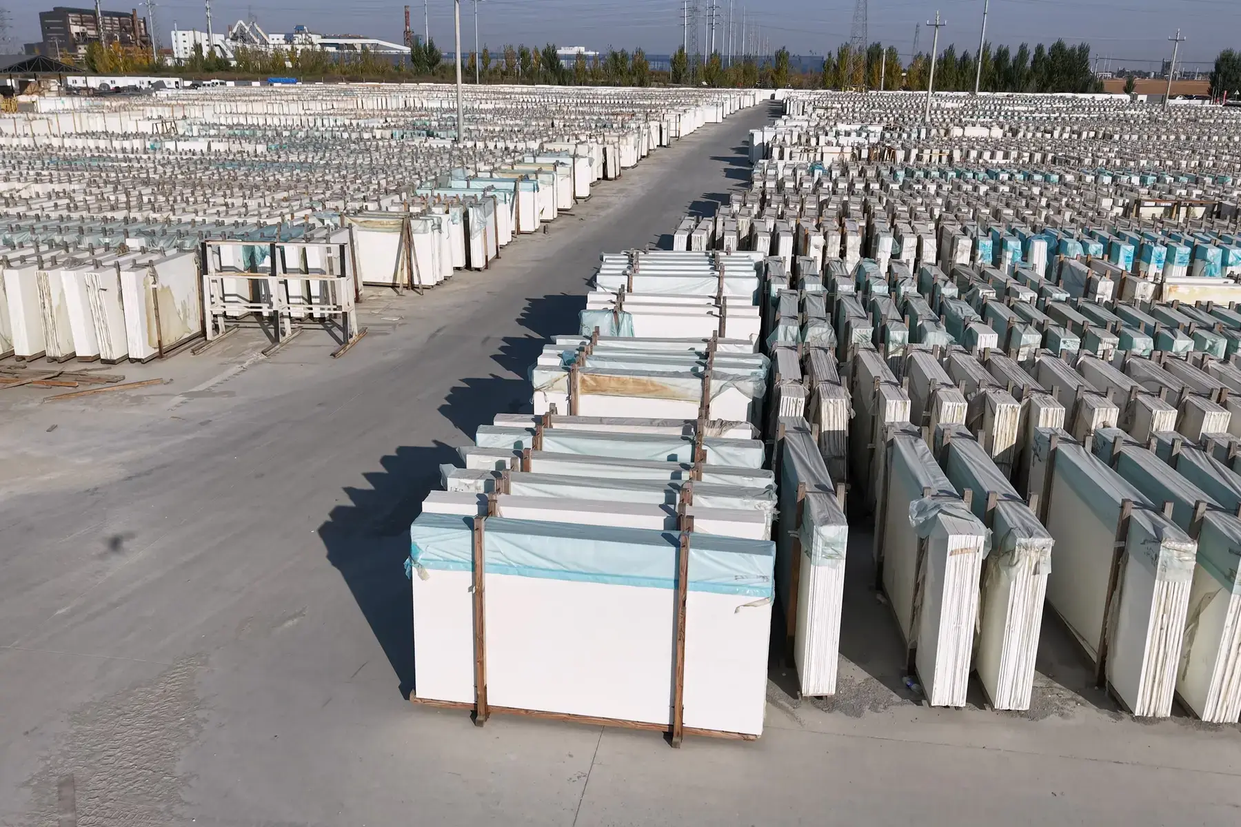 Pure white crystallized glass slabs stacked upright in a stock yard