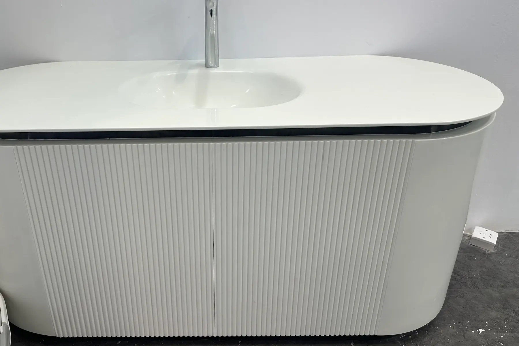 Rounded white vanity top with an integrated basin and chrome tap
